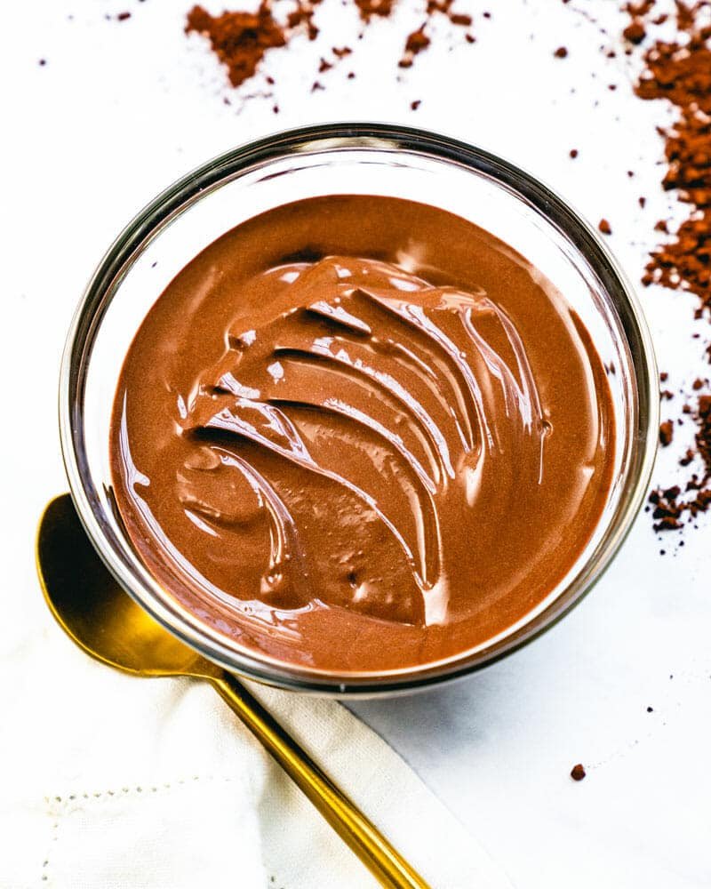 A bowl of creamy chocolate pudding with a gold spoon sitting next to it